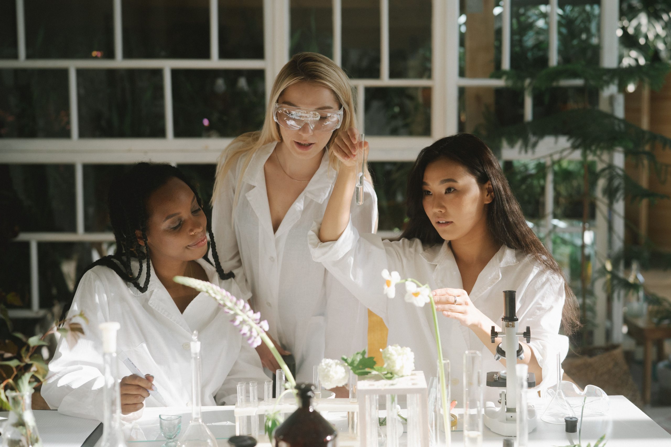 Three women scientists in a lab examining plants and using various laboratory equipment.